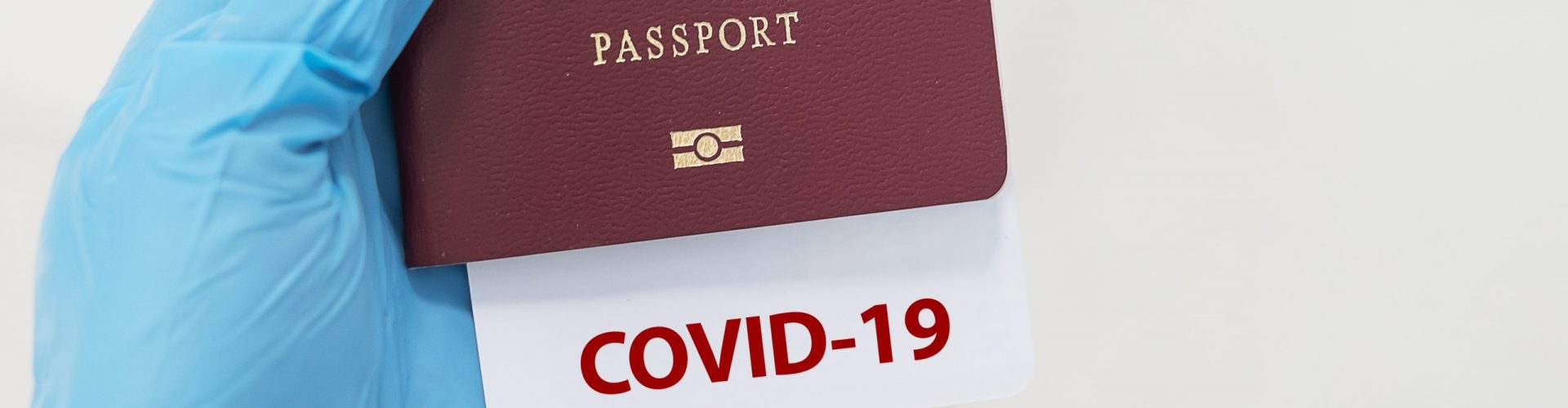 Hand wearing nitrile glove holding passport with COVID-19 note, Pay with Bitcoin for Thailand Elite Visa.